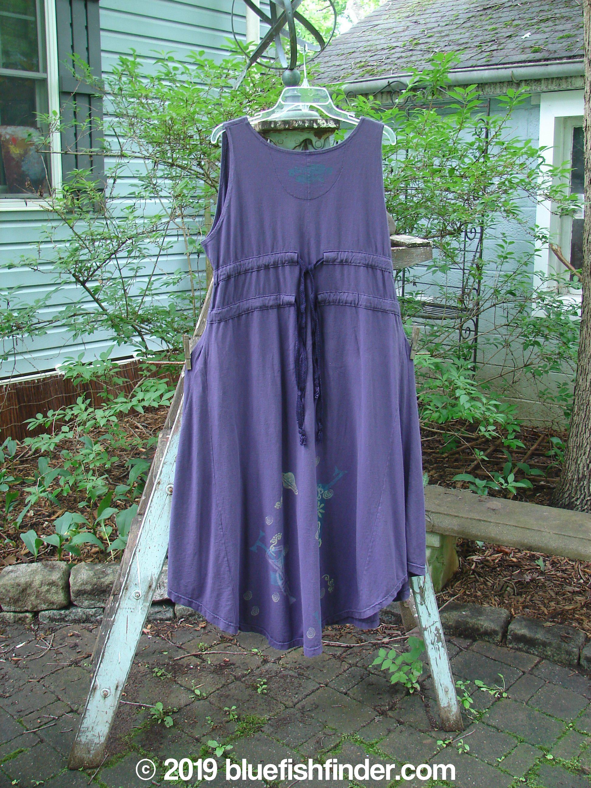 1994 Spin Jumper Mixed Purple Nuit Size 2: A medium weight cotton dress with empire waist, tie tunnels, V neckline, and sweeping hemline. Features nature, chair, and letter theme with leaves and vines. Bust 50, waist 50, hips 60. Lengths: side 51, front/back 58. Hem circumference 110 inches.