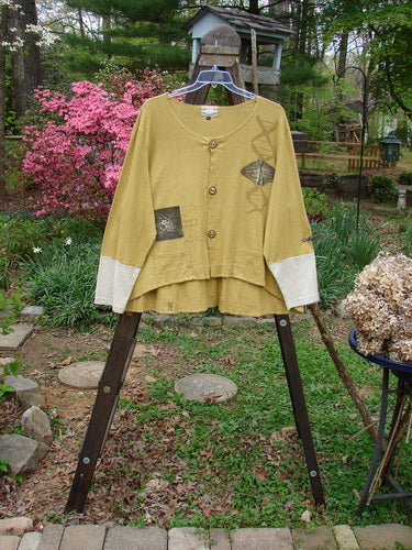 A yellow Philos Jacket from the 2000 Resort Collection in Gold. Made from a soft hemp cotton blend fabric. Features include a varying hemline, sectional horizontal panels, contrasting sleeves, lower pockets, taganut number buttons, rear flounce, and a rounded neckline. Classic Resort Biology theme paint adds a unique touch. Bust 58, Waist 58, Hips 60, Hem Circumference 80, Front Length 25, Back Length 30 inches.
