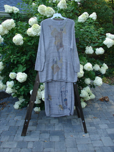 1995 Cotton Rayon Linear Column Sweater Duo Pike Dusk Mélange OSFA Size 1: A pair of grey pajamas on a wooden ladder, with a grey shirt featuring a picture on it. Clothes are also seen on a ladder and a rack.