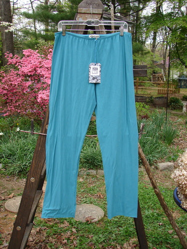 Barclay NWT Batiste Layering Pant Legging Unpainted Turquoise Size 2: A pair of pants on a clothes rack, perfect for layering. Made from featherweight cotton batiste, these pants have a forgiving, breezy feel. Waist 30-44, Hips 48, Inseam 28, Length 38.