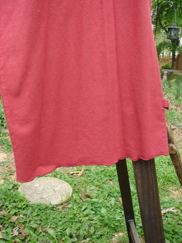 A red cloth from a clothes line, featuring a Barclay Crop Tiny Tab Pant in Ruby, size 2. The pant is made from medium weight cotton lycra and has a full elastic waistband. The image shows a close-up of a stone and a wooden post. The pant has a forgiving feel and is a perfect layering piece.