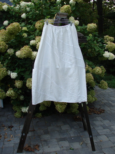 A white Barclay Linen Diagonal Skirt, size 2, on a rack. Features include exterior diagonal stitchery and a slightly shorter boxier length. Perfect condition.