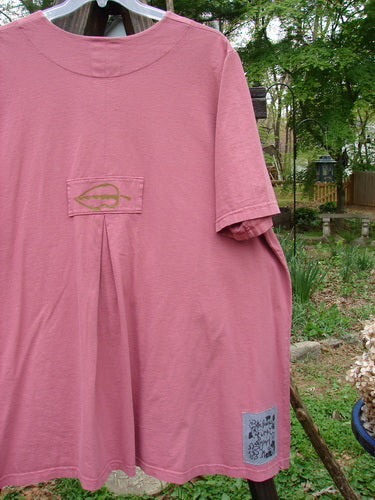 2000 Double Decker Pocket Top Garden Bug Rose Size 2: A pink shirt with a logo on it, featuring two front oversized pockets stacked on top of each other. Super flattering with pleated back line and tab.