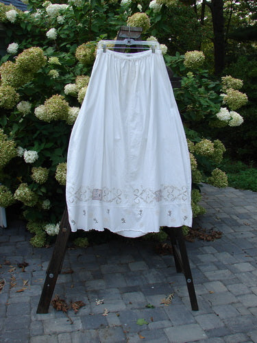 Barclay Linen Duet Skirt, a white skirt on a rack. Features include a widening bell shape, V-shaped insert, and tiny floral theme paint. Size 2.