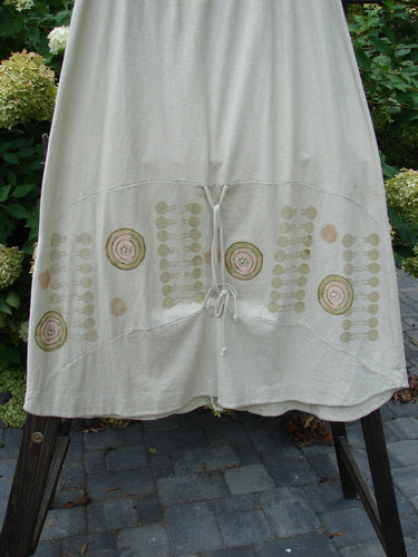 A white skirt with a pattern on it, made from a lovely hemp cotton blend. Features include a full elastic waistband, varying hemline, and creative adjustments. Size 2.