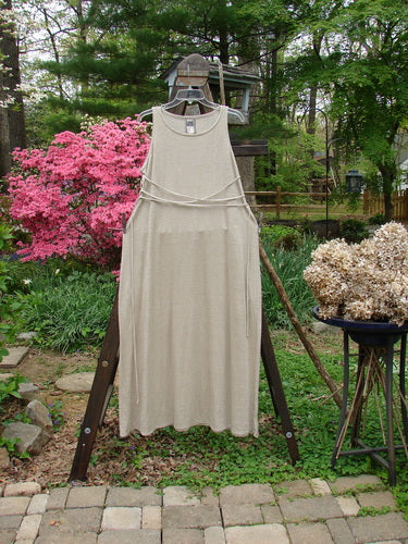 1998 Linen Knit Wrap Dress Unpainted Natural Size 1: A dress on a rack with a rounded neckline, smaller arm openings, and a flowing linen knit fabric.