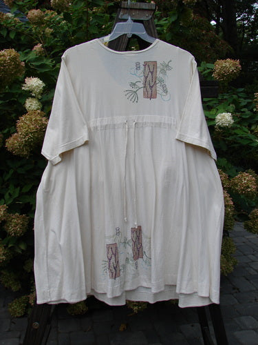 A white dress with a fish theme paint, featuring a drop tunnel kangaroo pocket and a rear drawcord. Barclay Tunnel Pocket Pull Over Dress Fish Natural Size 2.
