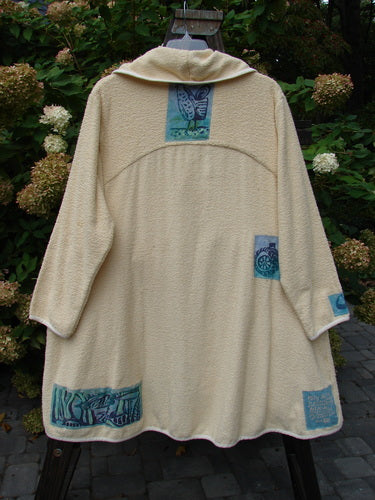 1996 Patched Cape Cod Coat with farm-themed patches and a deep V-neck collar. Oversized front pockets and a single button closure.