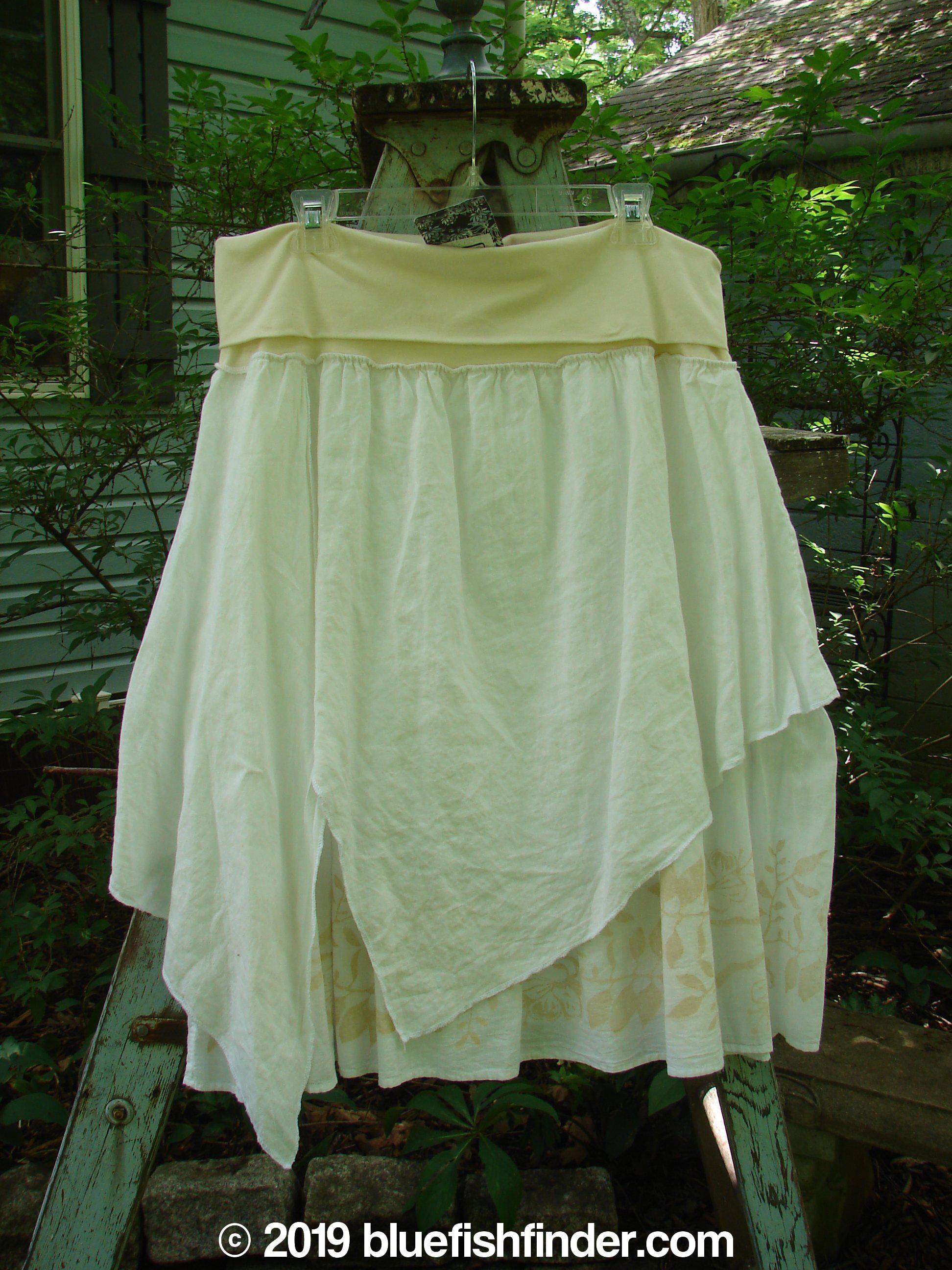 A white skirt with a wider, boxier crop shape and length, featuring a three-button front and three-quarter length cotton sleeves. The skirt has a full cotton paneled waistline with an outer layer of painted batiste set on the diagonal and a sweeping batiste ruffled under layer. The skirt has a dual length and measures 30 inches in full length. This Barclay NWT Batiste Draw Midi Meadow Trio White Size 2 is made from a combination of organic cotton and batiste.