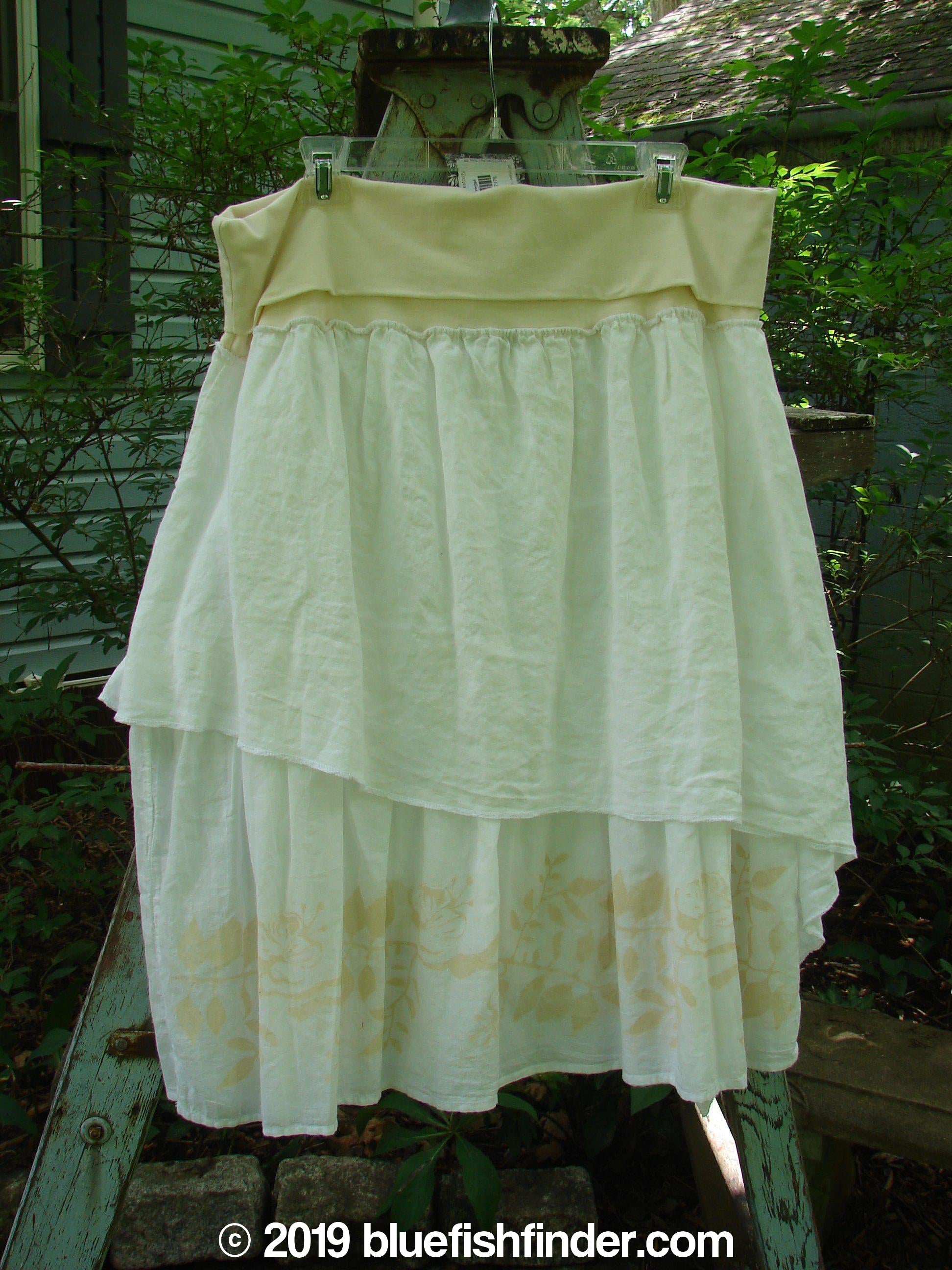 A white skirt and dress on a clothes line and rack, part of the Barclay NWT Batiste Draw Midi Meadow Trio in White. The skirt features a full cotton paneled waistline with a painted batiste outer layer and ruffled under layer. The dress has a wider, boxier crop shape with vertical pull cord accents. Perfect for spring or summer!