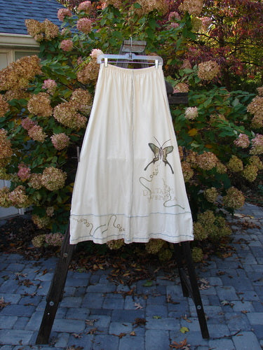 A white Sparrow Skirt from the 1998 Botanicals Collection, adorned with a butterfly design on Queen Anne's Lace. Made from organic cotton, it features a full elastic waistline, exterior stitchery, and lower sectional panels. Waist: 28-48, Hip: 48, Length: 38.