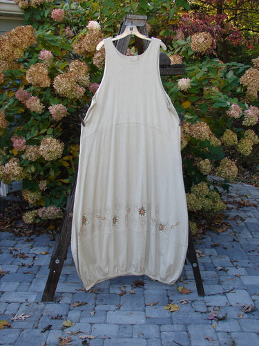 A white Libby Jumper dress on a rack, with a downward scooped waistline, side pockets, and a bubbled shape. Made from hemp cotton knit, it has a mid-weight material with extra drape and movement. Bust 52, waist 54, hips 56, length 58 inches.