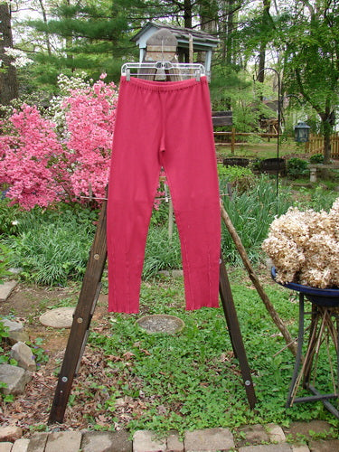 Barclay Cotton Lycra Layering Pinch Rib Pant Legging Unpainted Cranberry Size 2: A pair of pants on a clothes line in a garden, featuring a soft textured rib feel and fluttered lowers.