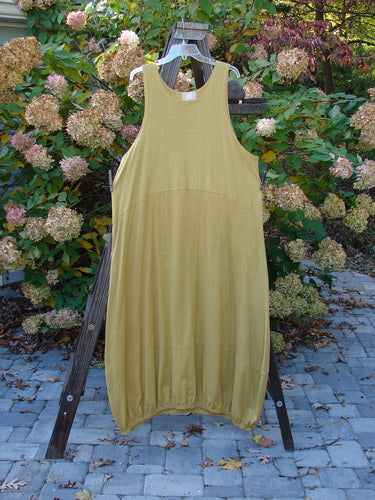 2000 Cotton Hemp Libby Jumper Unpainted Gold Size 2: A dress on a rack, yellow dress on a clothes rack, close up of a wood post, yellow dress on a ladder.
