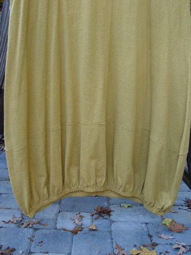 2000 Cotton Hemp Libby Jumper Unpainted Gold Size 2: A yellow curtain on a brick surface, a yellow fabric on a metal rack, and a close-up of a stone surface.