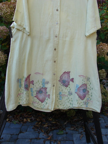 Barclay Linen Flower Button Gather Back Tunic Dress Undersea Plantain Size 2: A linen tunic dress with fish painted on it, featuring a button flower front, A-line shape, and elastic drop waistline.