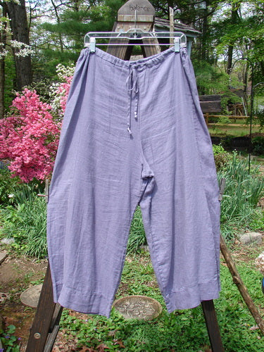 Barclay Linen Crop Drawstring Lounge Pant Unpainted Lavender Size 1: A pair of pants on a clothesline, featuring a banded waistband, crop length, and lower contouring with a banded cuff.
