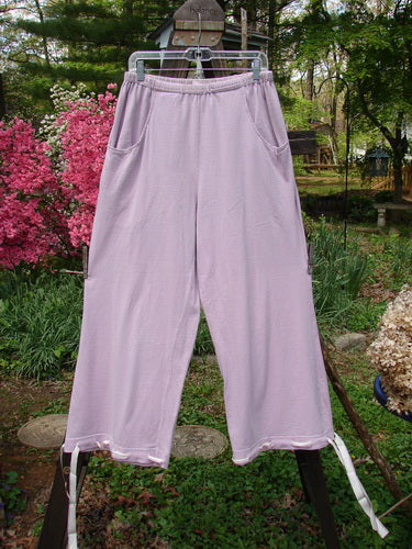 1999 Ribbon Pant Unpainted Orchid Size 1: A pair of pants on a clothesline with deep front bubble cargo pockets and button holes on each cuff with silk ribbon, giving a playful feel.