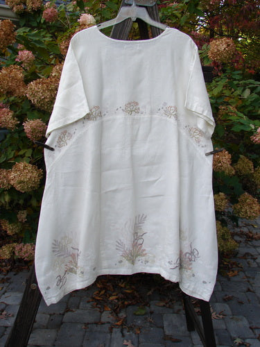 A Barclay Linen Urchin Tunic Dress in White, featuring a rounded neckline, A-line shape, and downward curved empire waist seam. The dress has wide short sleeves and a varying hemline, painted with an undersea theme. Bust 54, Waist 58, Hips 62, Sweep 80, Front Back Length 40, and Side Lengths 44 inches.