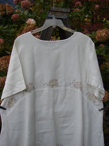 Barclay Linen Urchin Tunic Dress: A white shirt with a tree design on a metal swinger. Clothing, textile, pattern.