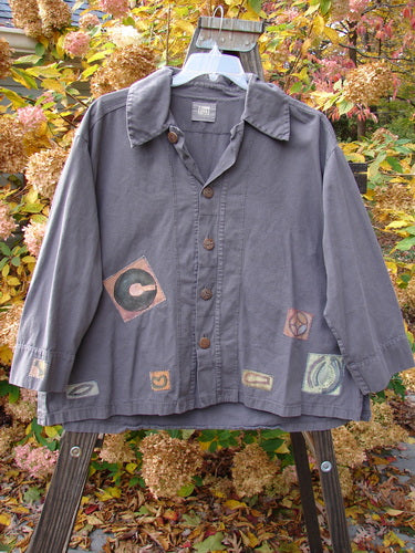 A Patched Elio Shirt in Iron, Size 2. A swingy, oversized shirt with unique stitchery, wooden buttons, and painted patches. Made from organic brushed cotton twill.
