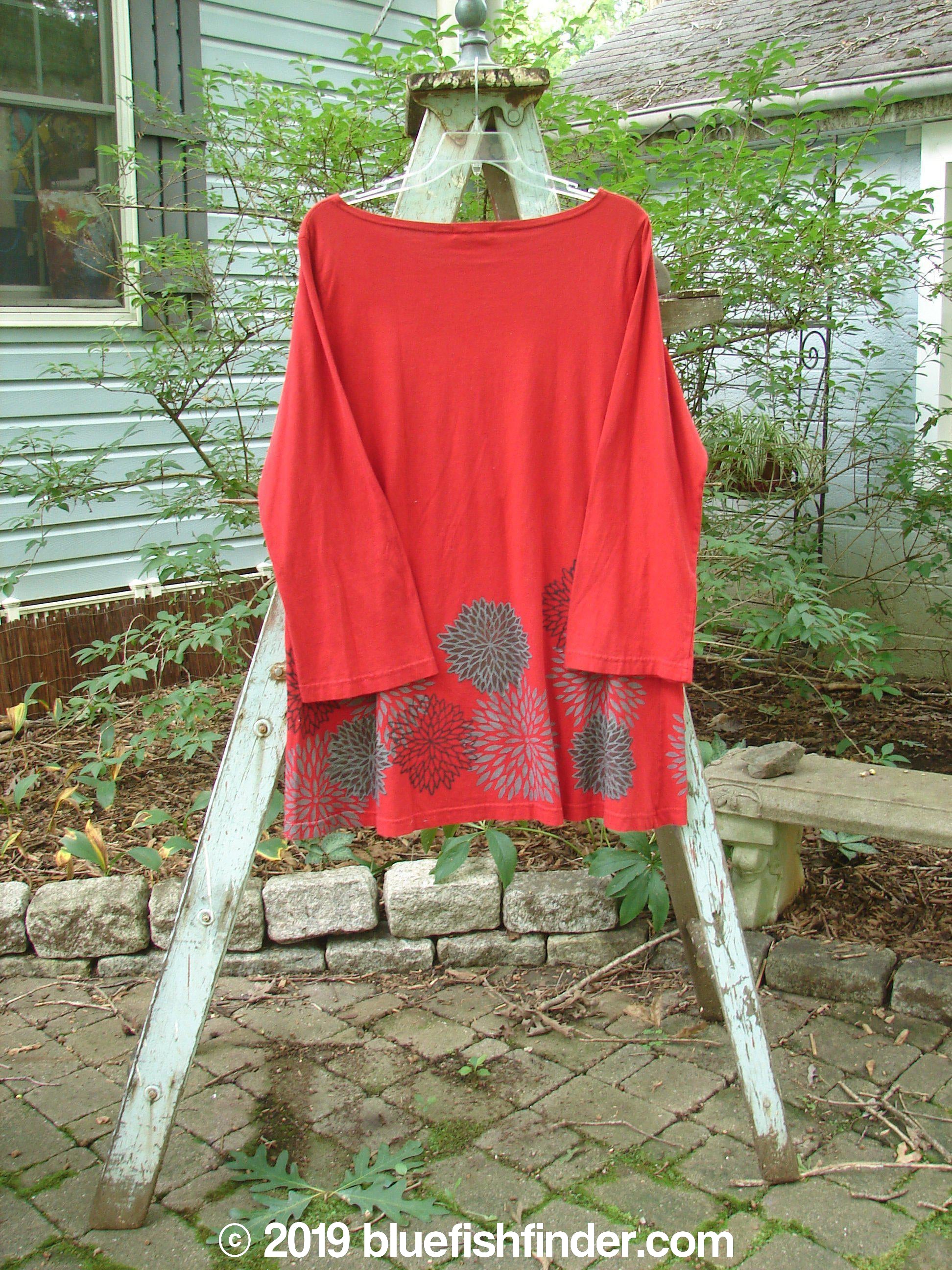 Barclay NWT Reverie Top Chrysanthemum Ruby Size 1: A red shirt with a beautifully painted chrysanthemum design, featuring a slight boat neckline and drop shoulders. The longer, A-line shape adds a flattering touch. Made from mid-weight organic cotton.