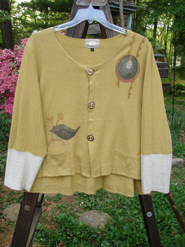 A yellow sweater with a bird on it, from the 2000 Cotton Hemp Philois Jacket Bio Dove Gold Size 1 collection. Features include a scooped varying hemline, contrasting sleeves, and rear flounce.