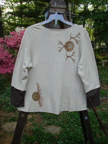 A white shirt with brown designs, featuring a scooped varying hemline, contrasting sleeves, and two lower pockets. This 2000 Cotton Hemp Philois Jacket Bio Dove Bark Size 1 is from the Resort Collection, made from a soft and densely knit fabric.