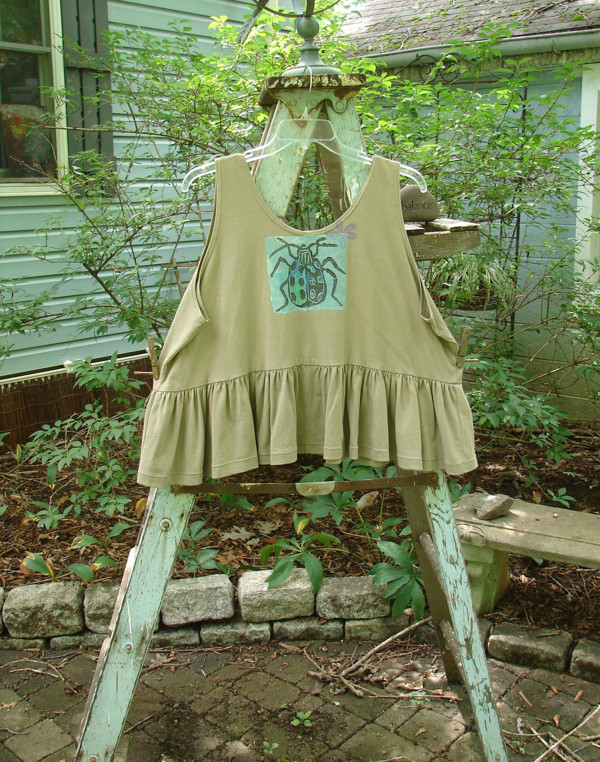 1992 Peplum Top Beetle Wheat OSFA: A vintage flounce top with a wide waist, yoked waist seam, and rounded neckline. Features a beetle-themed patch and a gathered bottom flounce.