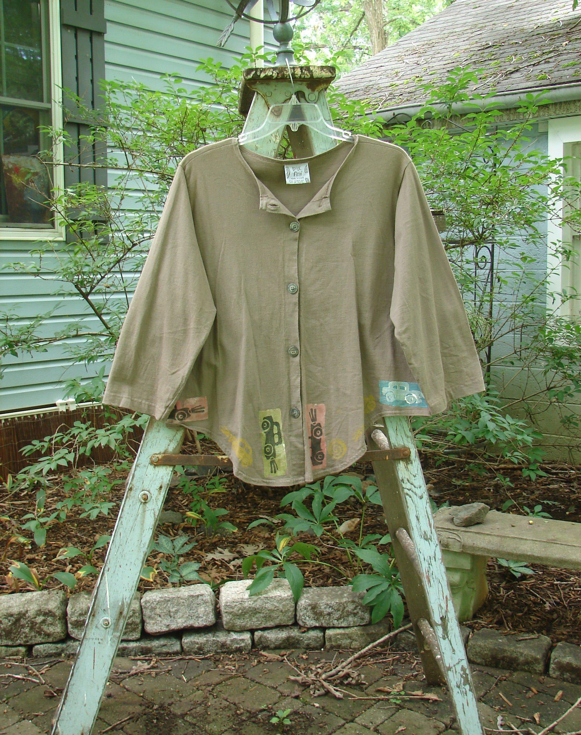 1993 Tie Back Jacket Car Bay Leaf OSFA: A vintage tie back jacket with a car theme paint design. Made from mid-weight cotton, it features a top vintage button, drop shoulders, and varying front and back hemline. Perfect condition.
