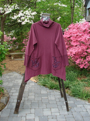Barclay Hemp Cotton Turtleneck Pocket Dress Silly Pup Loam Size 2: A purple shirt with a bird design on a wooden stand.