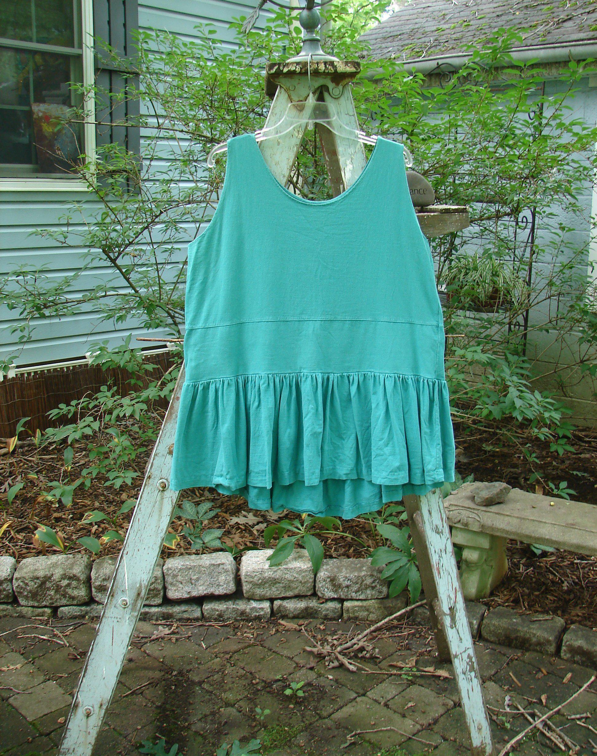 Image alt text: "1990 Button Tier Top in Turq on a ladder, featuring a gathered flounce, drop waistband, and ruffled hemline."