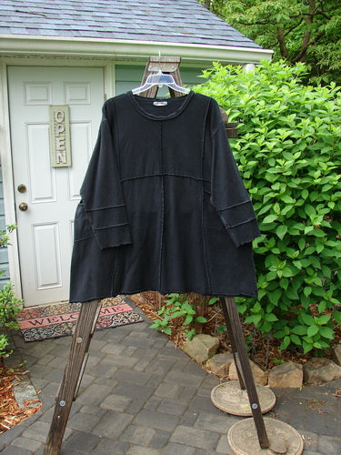 Image alt text: Barclay Hemp Cotton Dual Quadrant Dress on a swinger, featuring double quadrant exterior seams, a varying hemline, and two front drop exterior pockets. A piped and wavy neck and hemline, with an A-line flare and wider curly edged three-quarter length sleeves. Size 2.