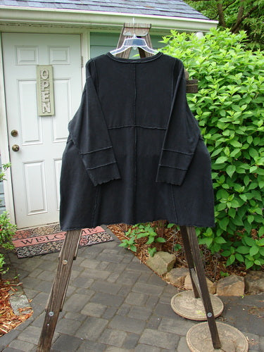 Image: A black coat on a clothes rack.

Alt text: Barclay Hemp Cotton Dual Quadrant Dress in Unpainted Black, Size 2, hanging on a clothes rack.