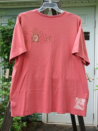 A red t-shirt with a logo on a clothes rack. From the 1998 Summer Collection, this short-sleeved tee features a fish card theme paint specific to Summer 98. Made from 100% organic cotton, it has drop shoulders, a ribbed neckline, and a signature Blue Fish patch. Bust: 52, Waist: 52, Hips: 52, Length: 32.