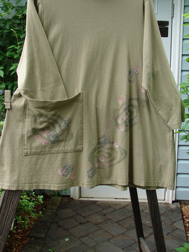 1996 Ramble Dress Follow Path Bottlecap Size 1: A green shirt with a pocket on it, featuring a unique design.