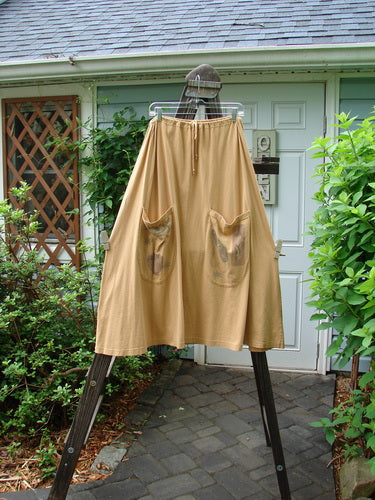 Image alt text: "1994 Scoop Pocket Skirt Hot Pepper Dijon Size 1: A pair of pants with painted pockets on a clothesline"