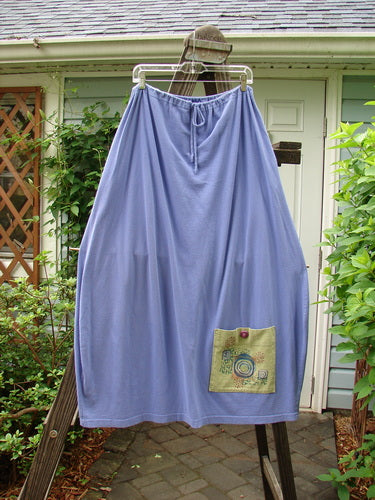 1997 Big Pocket Skirt Bolder Skylark Size 1: A long blue skirt with a unique bell-shaped bottom, drawstring waistline, and a super giant lower exterior pocket with a vintage blue fish button closure.
