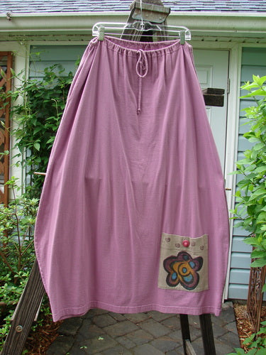 1997 Big Pocket Skirt with single flower patch. Pink skirt with unique bell-shaped bottom, drawstring waistline, and giant exterior pocket.
