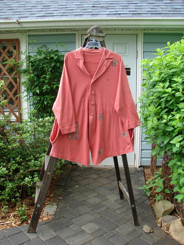 A pink Boulevard Jacket with a button-accented collar, tabbed back, and shirttail hemline. Features a pinwheel theme. Size 2.