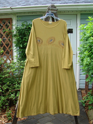 Image alt text: "1999 Curved A Line Dress in Rolling Gold, size 1, on a clothes rack with a close-up of a plant in the background"