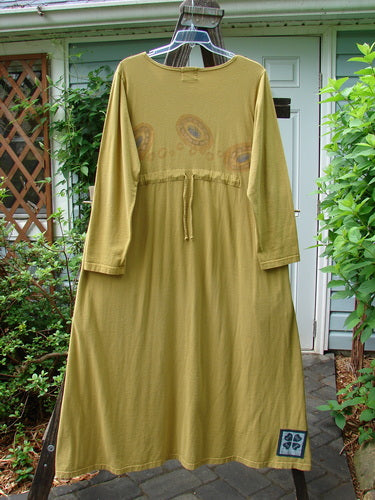 Image alt text: "1999 Curved A Line Dress in Rolling Gold, size 1, on a clothes rack with a plant in the background"