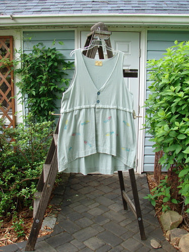 Barclay Little Tree Vest Dragonfly Fish Cucumber Size 1: A white shirt with buttons on a clothes rack outside of a house, featuring a close-up of a plant and a wooden ladder.