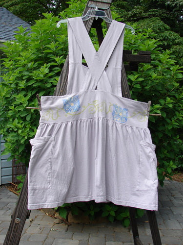 1995 Overall Jumper Daisy Curl Lavender OSFA: A white overall with a cross-back, featuring a creatively cut overall bib, a shorter length, and a full gathered and wide playful skirt.