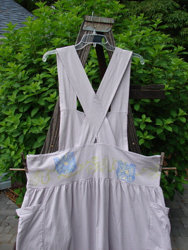 A lavender overall jumper with a playful skirt, crisscross back straps, and daisy theme paint. Vintage 1995 Blue Fish Clothing.
