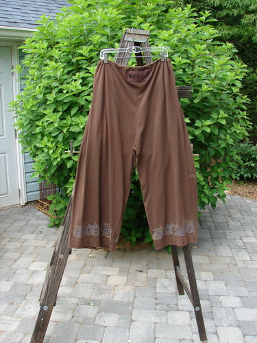 Image alt text: "1992 Buttonloop Pant Grape Leaf Bay Leaf OSFA: A pair of brown pants with a full drawstring waistline, deep side pockets, and a longer inseam measurement. Made from medium weight cotton."