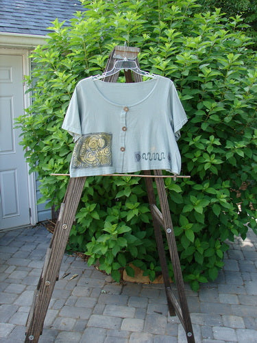 1993 Travel Top Many Moons Ocean Size 2: A shirt on a wooden stand with a patch on it. Perfect condition. Lovely crop shape with rare wooden buttons.