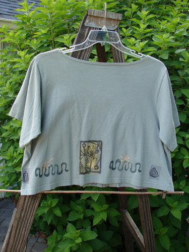 1993 Travel Top Many Moons Ocean Size 2: A shirt on a swinger with a drawing of a person. Active shirt with a close-up of a plant.