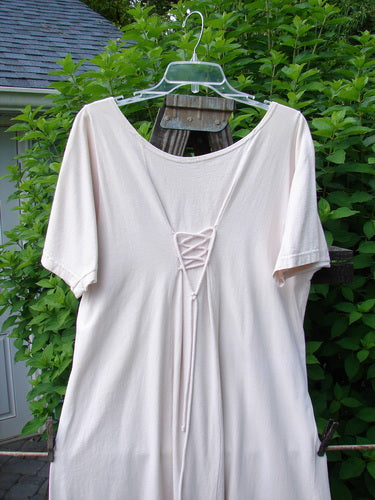 1994 Loop Dress Magic Garden Tea Dye Smaller OSFA: A white shirt on a clothes hanger, featuring a sweeping A-lined shape, dual cord lacings, and a super flared hemline.