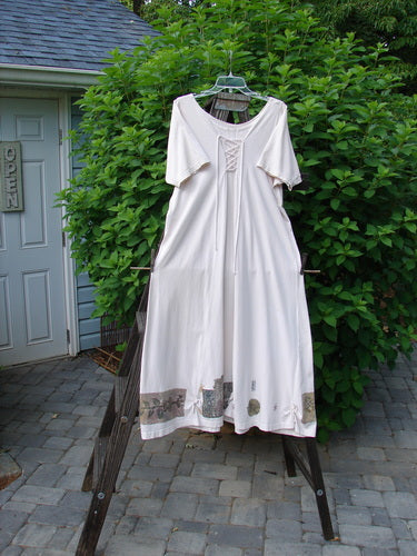 1994 Loop Dress Magic Garden Tea Dye Smaller OSFA: A white dress on a rack with lace-up front and flared hemline.